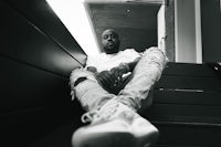 a black and white photo of a man sitting on stairs